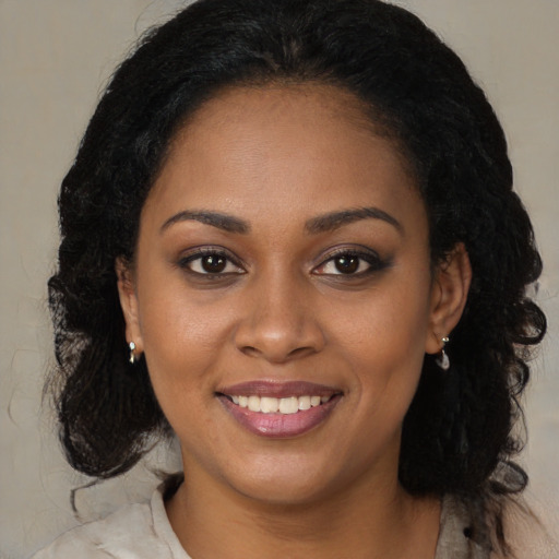 Joyful black young-adult female with long  brown hair and brown eyes