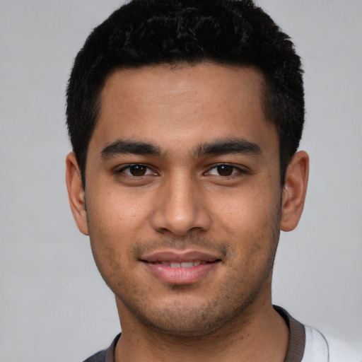 Joyful latino young-adult male with short  black hair and brown eyes