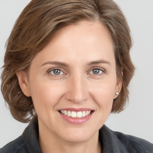 Joyful white young-adult female with medium  brown hair and grey eyes