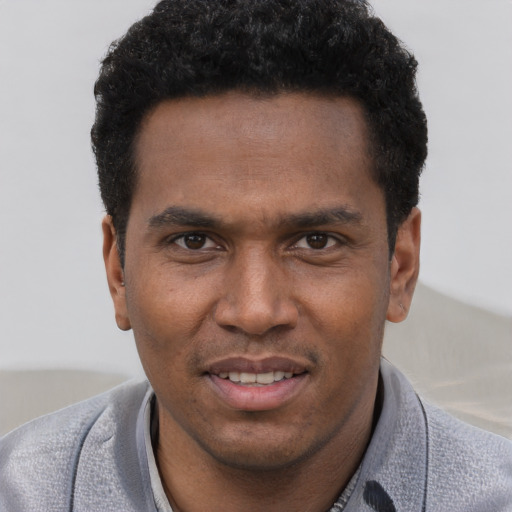 Joyful black young-adult male with short  black hair and brown eyes