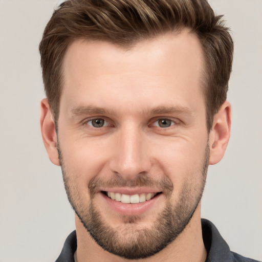 Joyful white young-adult male with short  brown hair and grey eyes