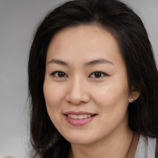 Joyful asian young-adult female with long  brown hair and brown eyes