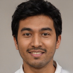 Joyful latino young-adult male with short  black hair and brown eyes