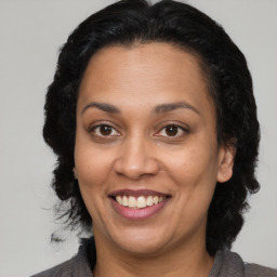 Joyful latino adult female with medium  brown hair and brown eyes