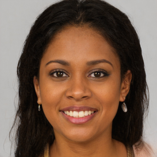 Joyful black young-adult female with long  brown hair and brown eyes