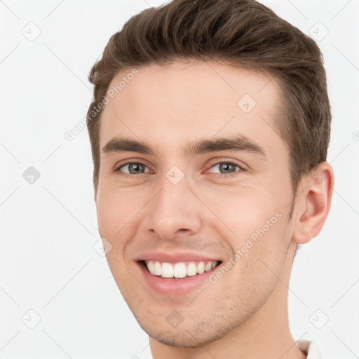 Joyful white young-adult male with short  brown hair and grey eyes