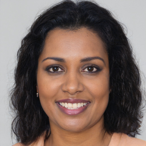 Joyful black young-adult female with long  brown hair and brown eyes