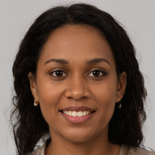 Joyful black young-adult female with long  brown hair and brown eyes