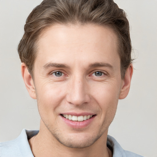 Joyful white young-adult male with short  brown hair and grey eyes