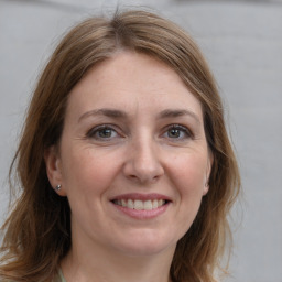 Joyful white adult female with long  brown hair and grey eyes