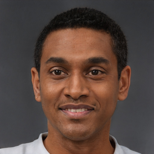 Joyful black adult male with short  black hair and brown eyes