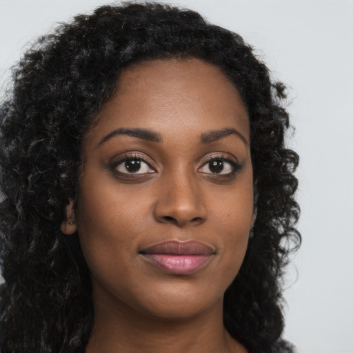 Joyful black young-adult female with long  brown hair and brown eyes