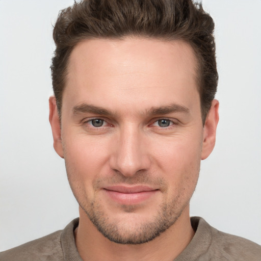 Joyful white young-adult male with short  brown hair and grey eyes