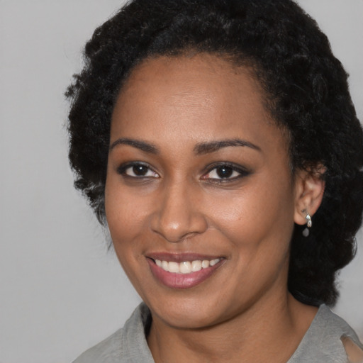 Joyful black young-adult female with short  brown hair and brown eyes