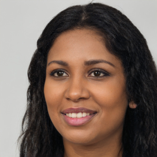 Joyful black young-adult female with long  black hair and brown eyes