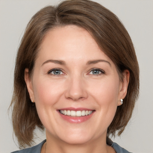 Joyful white adult female with medium  brown hair and grey eyes