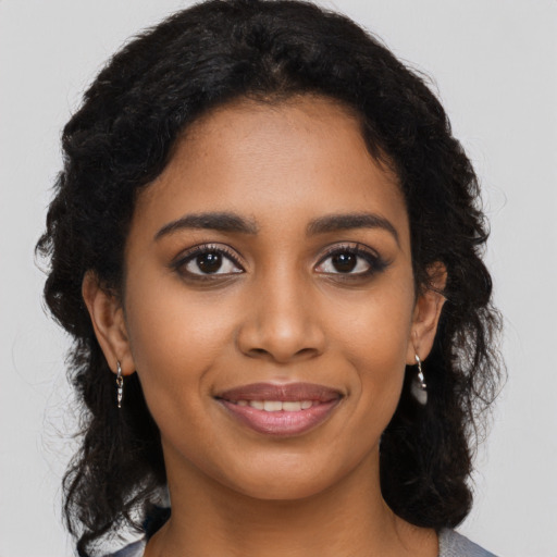 Joyful black young-adult female with long  brown hair and brown eyes
