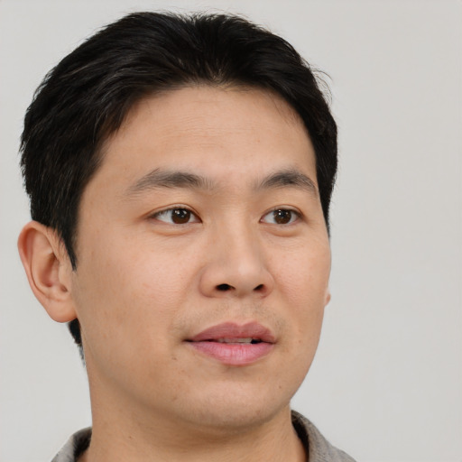 Joyful asian young-adult male with short  brown hair and brown eyes