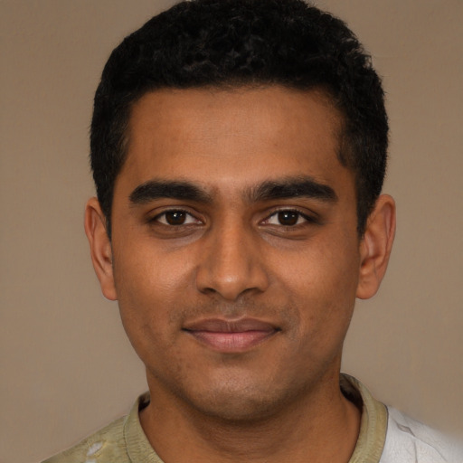 Joyful black young-adult male with short  black hair and brown eyes