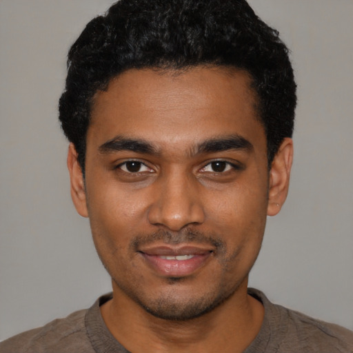 Joyful black young-adult male with short  black hair and brown eyes