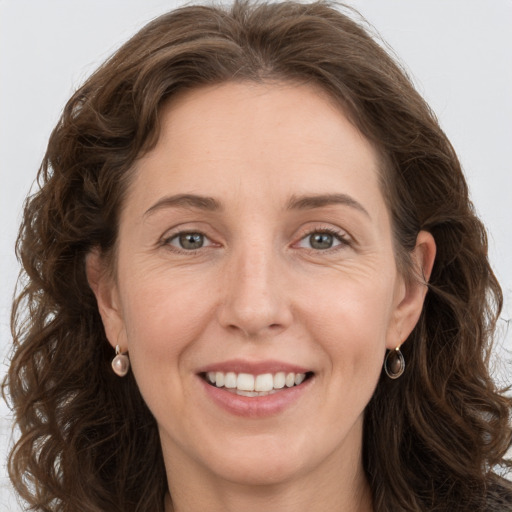 Joyful white adult female with long  brown hair and grey eyes