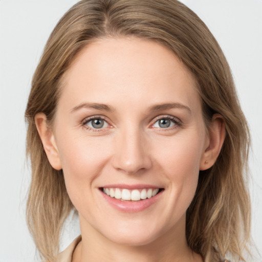 Joyful white young-adult female with medium  brown hair and grey eyes