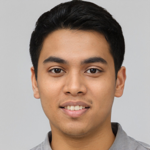 Joyful latino young-adult male with short  black hair and brown eyes