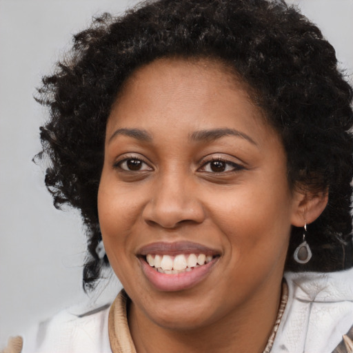 Joyful black young-adult female with long  brown hair and brown eyes