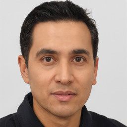 Joyful latino young-adult male with short  black hair and brown eyes