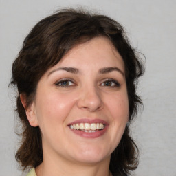 Joyful white young-adult female with medium  brown hair and green eyes