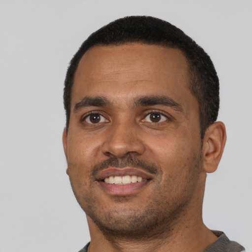 Joyful black young-adult male with short  black hair and brown eyes