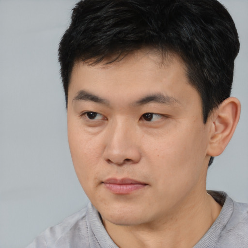 Joyful asian young-adult male with short  brown hair and brown eyes