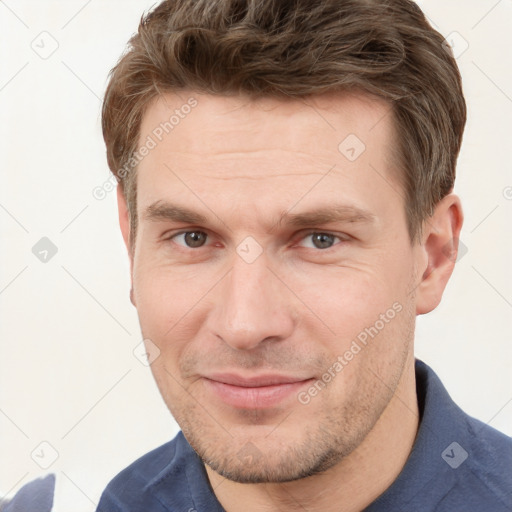 Joyful white young-adult male with short  brown hair and grey eyes