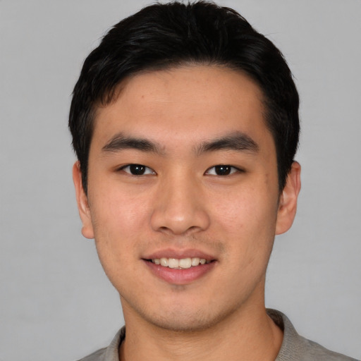Joyful asian young-adult male with short  black hair and brown eyes