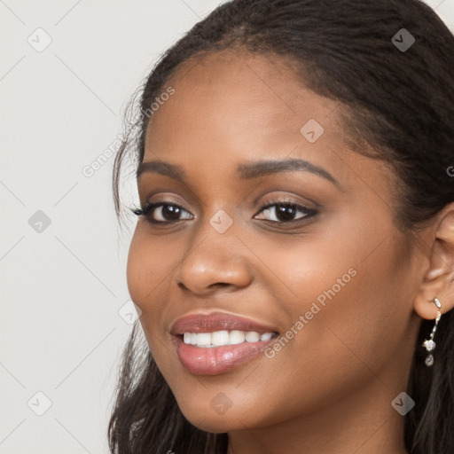 Joyful black young-adult female with long  brown hair and brown eyes