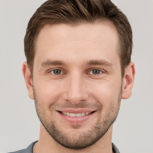 Joyful white young-adult male with short  brown hair and grey eyes