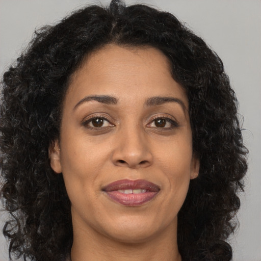 Joyful black adult female with long  brown hair and brown eyes