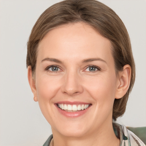 Joyful white young-adult female with medium  brown hair and grey eyes