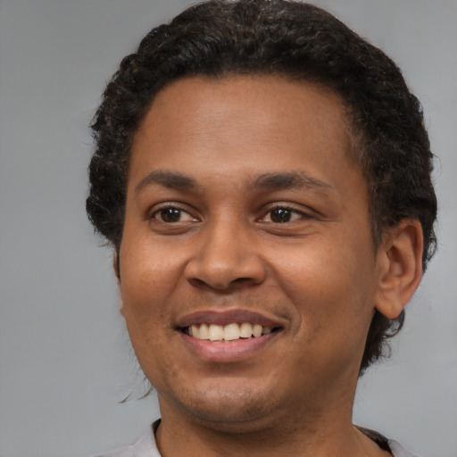 Joyful black young-adult male with short  brown hair and brown eyes