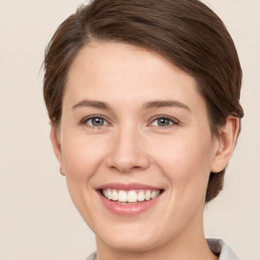 Joyful white young-adult female with short  brown hair and grey eyes