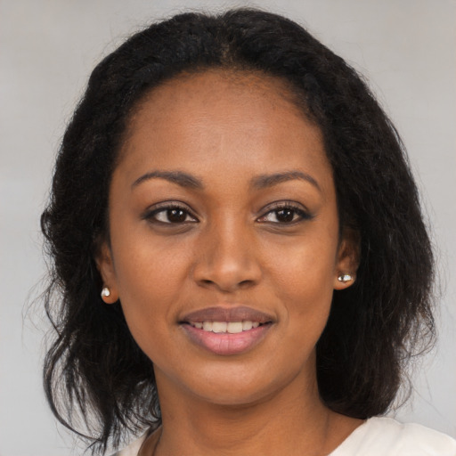 Joyful black young-adult female with long  black hair and brown eyes