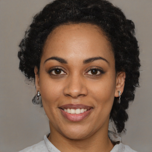 Joyful black young-adult female with short  black hair and brown eyes