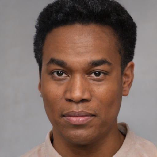 Joyful black young-adult male with short  black hair and brown eyes