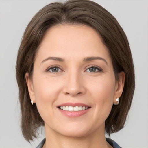 Joyful white young-adult female with medium  brown hair and grey eyes