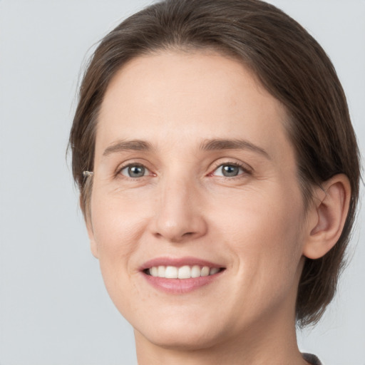 Joyful white young-adult female with medium  brown hair and grey eyes