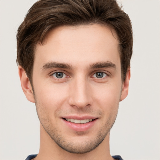 Joyful white young-adult male with short  brown hair and grey eyes