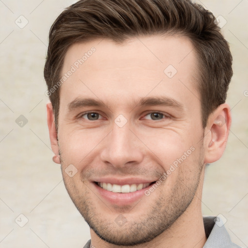 Joyful white young-adult male with short  brown hair and grey eyes