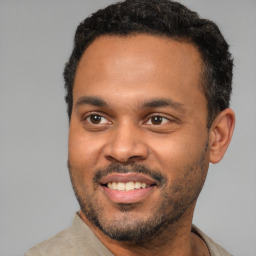 Joyful black young-adult male with short  black hair and brown eyes