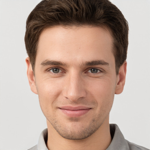 Joyful white young-adult male with short  brown hair and grey eyes