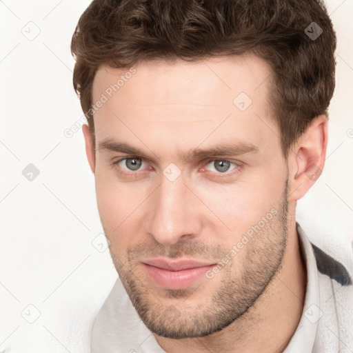 Joyful white young-adult male with short  brown hair and grey eyes